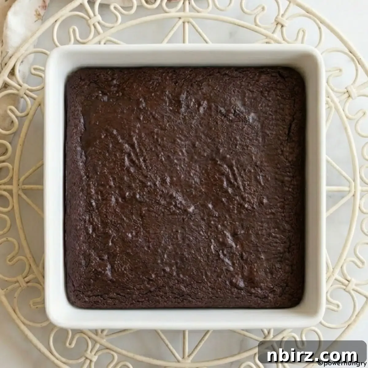 Decadent Grain-Free Vegan Carob Almond Brownies 8 Freshly baked vegan carob almond flour brownies cooling on an antique wire rack, ready to be sliced.