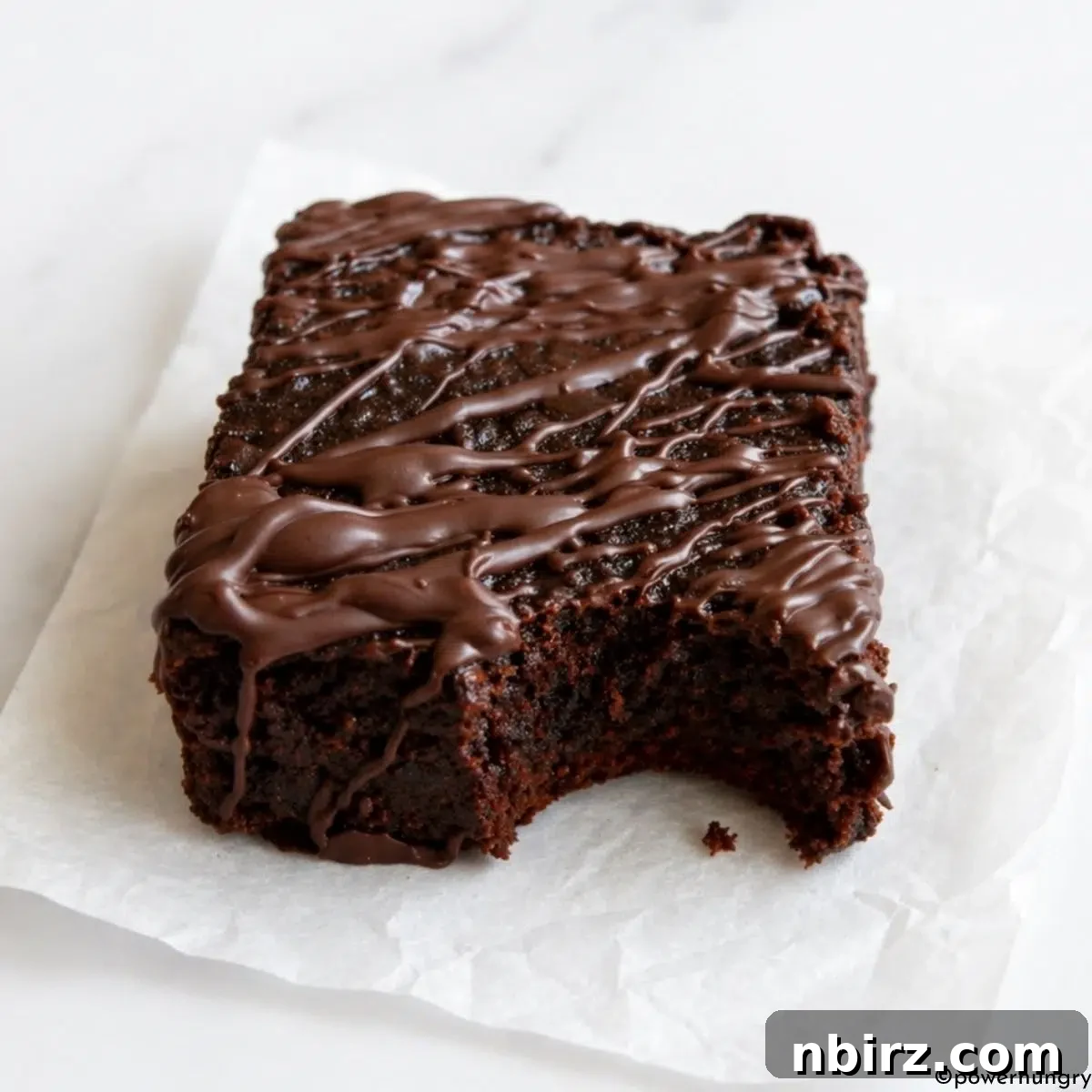 Decadent Grain-Free Vegan Carob Almond Brownies 9 Close-up of a vegan carob almond flour brownie with a bite taken out, showing its moist, dense, and rich interior.