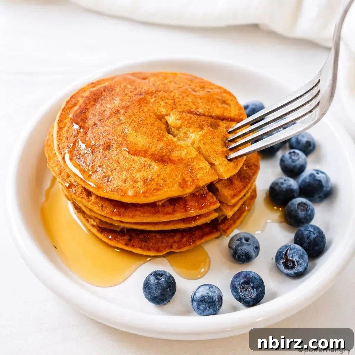 4-Ingredient High-Protein Vegan Red Lentil Pancakes 2 red lentil pancakes on a white plate with blueberries