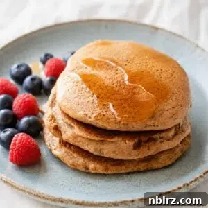 Fluffy Gluten-Free Vegan Buckwheat Pancakes 9 hero image of 3 vegan buckwheat pancakes with maple syrup and fresh berries on a blue plate